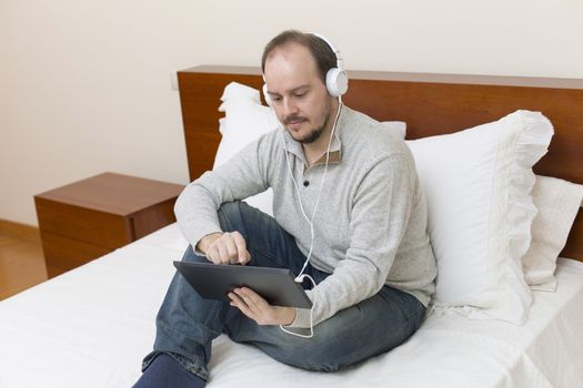 casual man working with a tablet pc in bed
