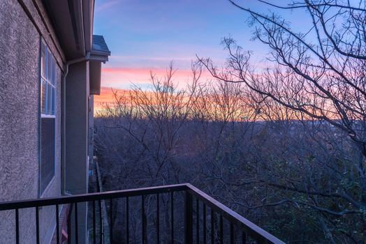 Aerial view from balcony of typical park side apartment complex during winter sunrise with dramatic cloud reflection on windows