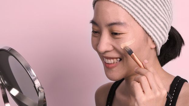 Asian girl or woman 40 years old beautiful face with japanese look making up by foundation liquid and cosmetic brush on sensitive skin for helping her complexion look flawless and no retouch.