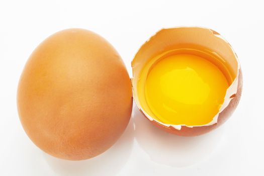 Two brown eggs on a white background. One egg is broken.