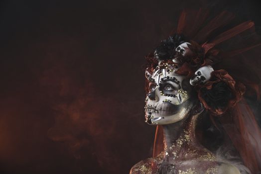 Santa Muerte Young Girl with Artistic Halloween Makeup and with Sculls in her Hair