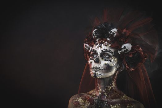 Santa Muerte Young Girl with Artistic Halloween Makeup and with Sculls in her Hair