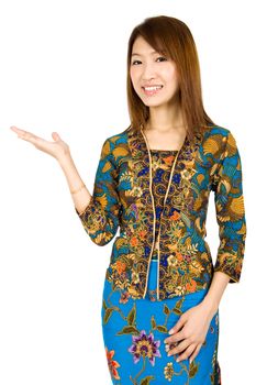 Southeast Asian girl wearing batik kebaya holding hand showing something, standing isolated on white background.