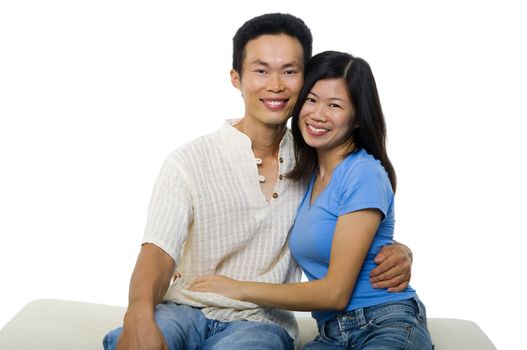 Young Asian couple sitting on sofa with smiling face, on white background.