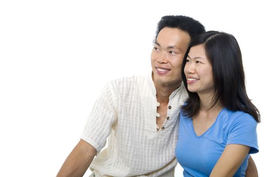 Young Asian couple sitting on sofa with smiling face, looking at side, on white background.