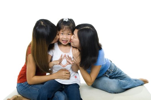 Asian family kissing little girl face on white background. Sisterly love.