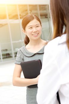 Asian businesswoman having conversation, office building as background
