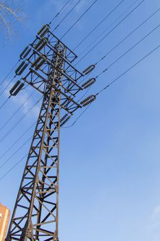 High-voltage power line 110 kV, metal support, wires, insulators, against the blue sky, vertical shot.