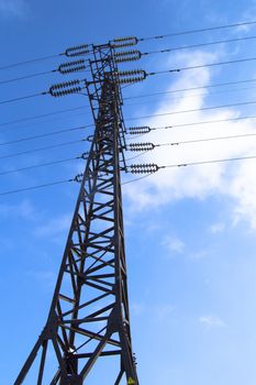 High-voltage power line 110 kV, metal support, wires, insulators, against the blue sky, vertical shot.