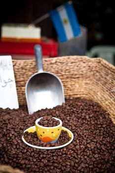 Yellow coffee cup on top of coffee beans pile full with copfee beans