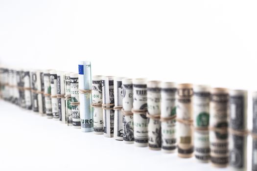 Row of dollar rolls with a euro banknote in the middle isolated on white