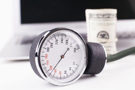 sphygmomanometer on white with silver laptop an money in the background