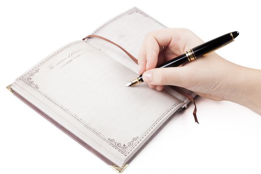 Female hand writing on empty page in diary with fountain pen
