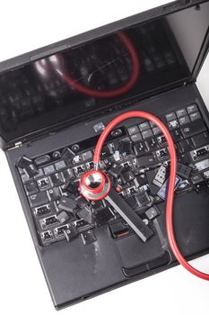 Broken black laptop with destroyed keyboard and smashed monitor with red stethoscpoe