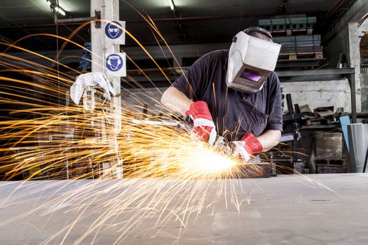 Worker Grinding metal in a workshop with sparks flying