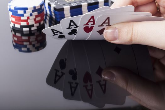 Woman holds aces poker cards with reflection and casino chips in the background