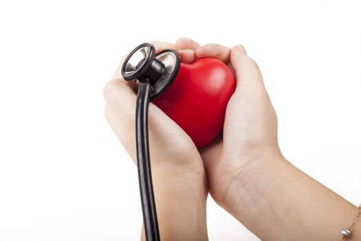 Holding red heart in two hands with black stethoscope in the background isolated on white