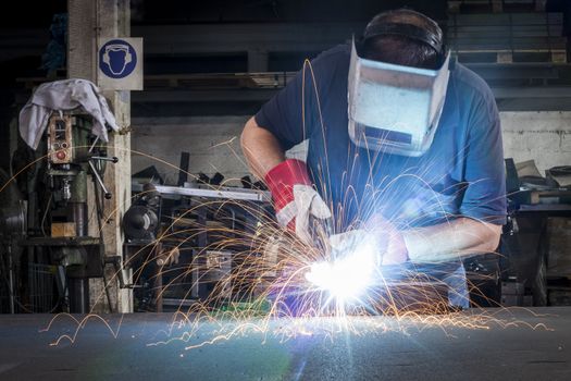 Metal welding in steel workshop with sparks and bright light