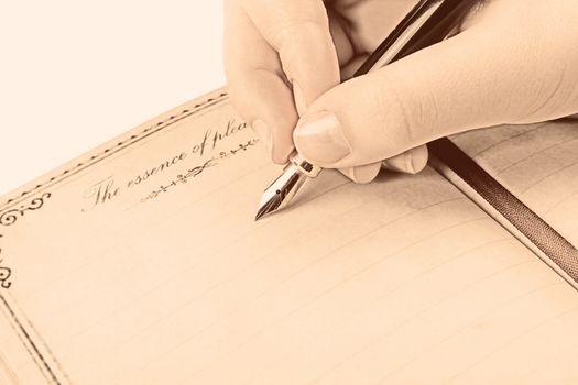 Female hand writing empty page in diary with fountain pen