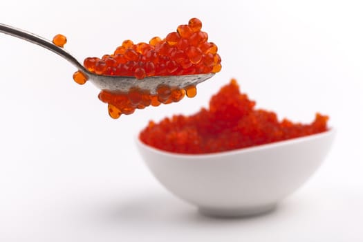 Red Caviar on teaspoon with white bowl isolated on white background