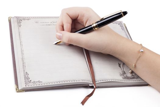 Female hand writing empty page in diary with fountain pen