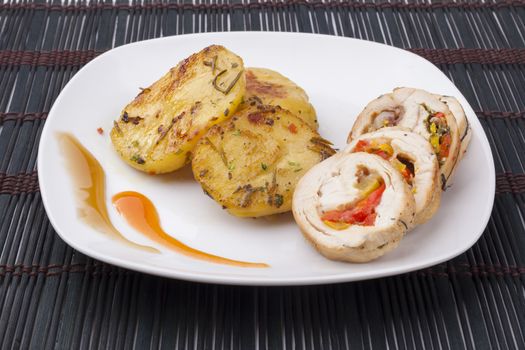 Coocked yellow color poatao with spices and herbs as a garnish to  chicken meat on dark background