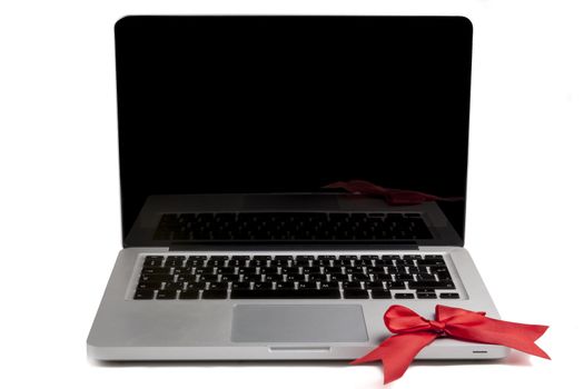 Silver Laptop with blank black screen and red bow on the keyboard isolated on white background