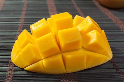 Sliced mango cubes close-up on dark table background