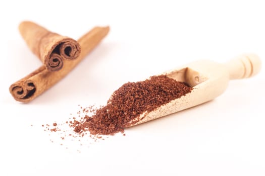 Cinnamon stick and powder on wood spoon isolated on white background