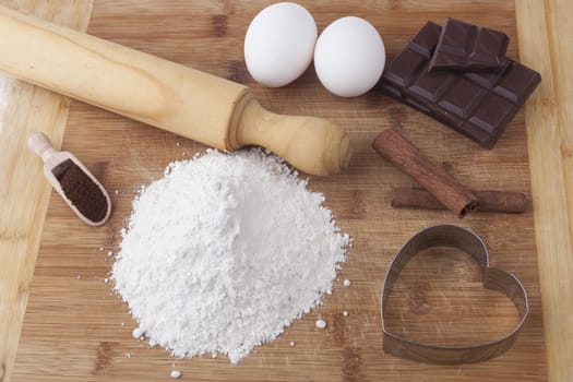 Baking ingredients and tools on brown wood cutting board