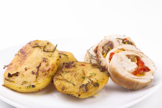 Coocked yellow color poatao with spices and herbs as a garnish to  chicken meat isolated on white