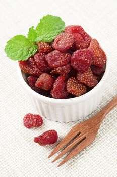 Dried Strawberries in white cup on tablecloth background.