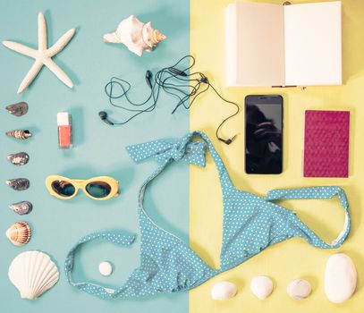 flat lay of beach holiday items: swimming suit,  sunglasses,  smartphone