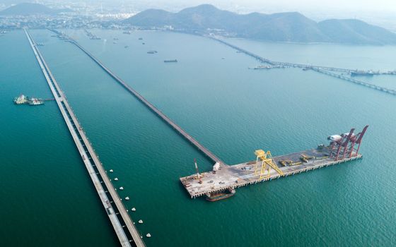 Aerial view of container ship in import - export business industry in Sriracha industrial port, Chonburi, Thailand.