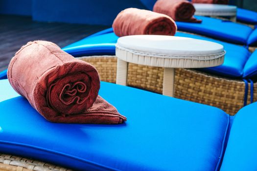image of Folded towels on lounge chairs beside pool