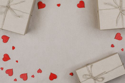 Gift boxes wrapped in brown craft paper and tied with rope with red hearts with copy space flat lay top view border frame