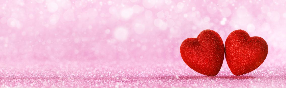 Two red glitter hearts on bright heart lights bokeh background