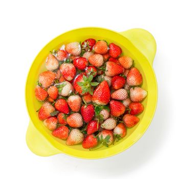 fresh red strawberry soaking in water in plastic bowl