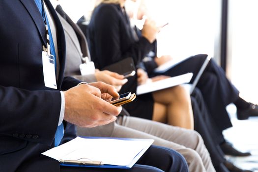 Business men using mobile phones sitting at training room, conference hall