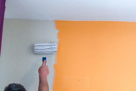 Hand with paint roller renovating. Painting a wall with white paint