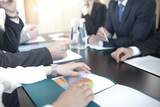 Business people discussing documents at workplace in office sitting around the table