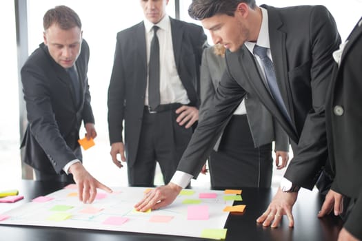 Business people team developing plan on office desk using stick notes