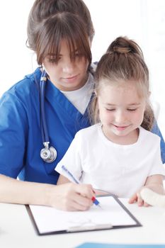 Child patient and young female doctor writing diagnosis