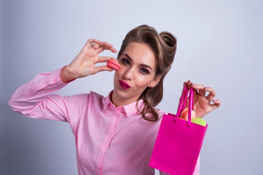 Funny smiling blond woman eating colorful macaroons