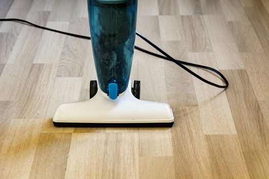 Vacuum cleaner on a light parquet floor. Interior shot.