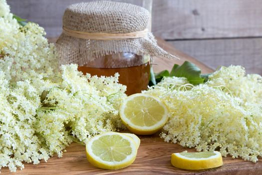 Fresh elder flowers with lemon and honey on a wooden background