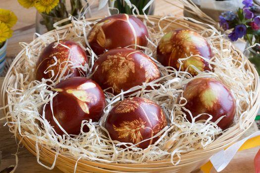 Easter eggs dyed with onion peels, with a pattern of fresh herbs, in a wicker basket