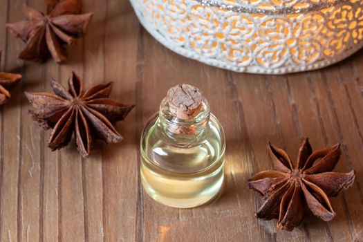A bottle of essential oil with star anise on a table