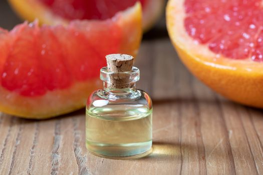 A bottle of essential oil with fresh pink grapefruit in the background