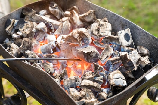 brazier with the burning coals standing on a grass